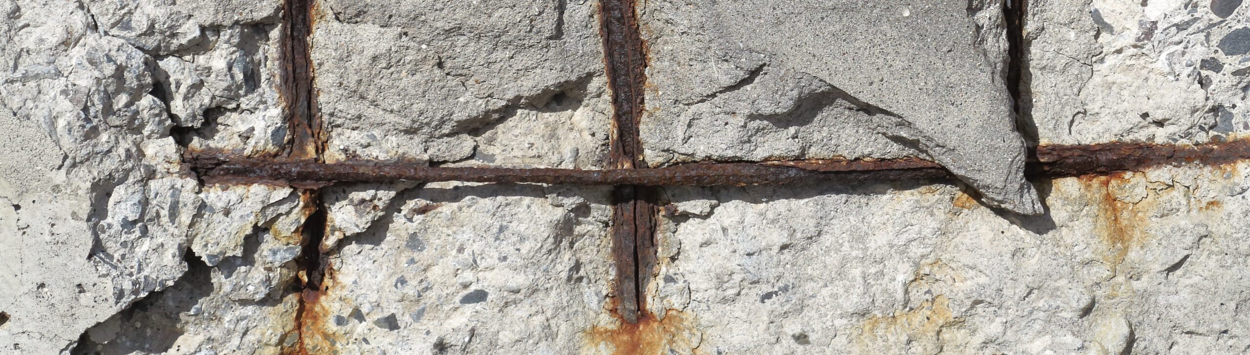 Concrete spalling may expose corroded reinforcing steel, but the visible damage does not necessarily reveal its full extent