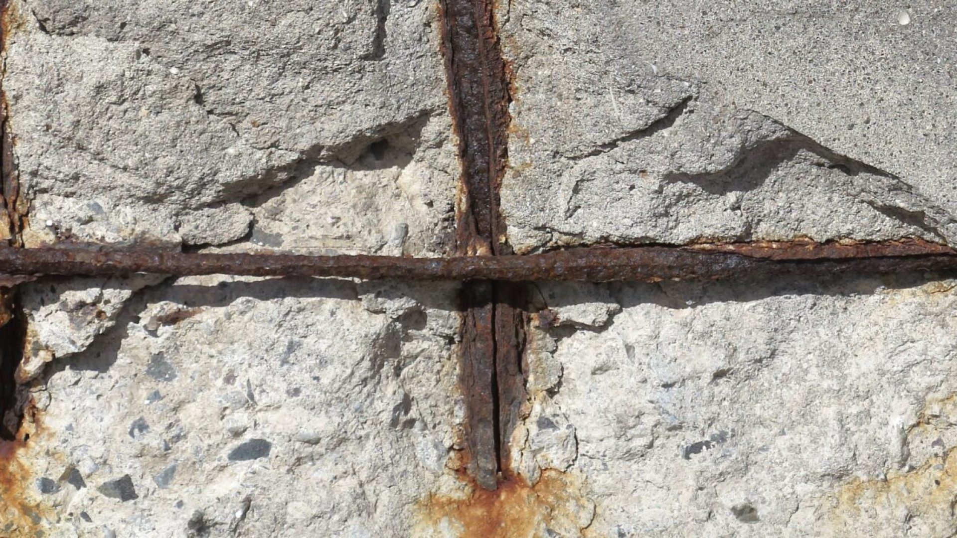 Concrete spalling may expose corroded reinforcing steel, but the visible damage does not necessarily reveal its full extent